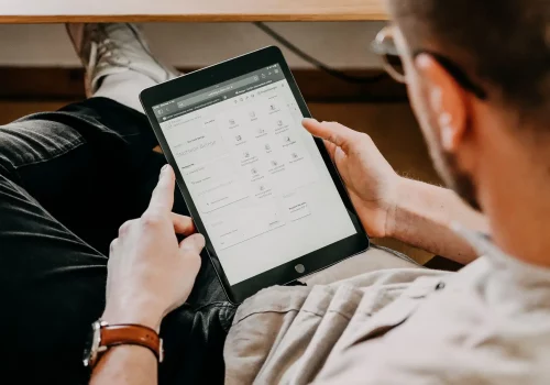 Lukas Kölzer, Steuerberater und Inhaber der Kölzer Steuerberatungsgesellschaft in Landau von schräg hinten aufgenommen. In seinen Händen haltend, ist ein Tablet zu sehen, das das Arbeiten einer digitalen Kanzlei symbolisiert.